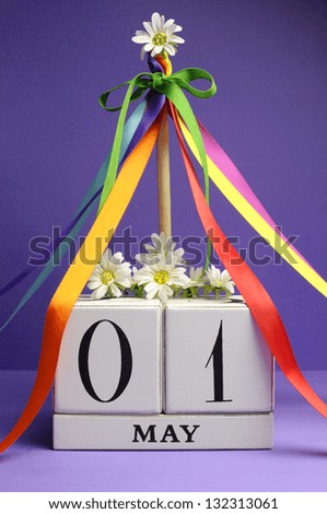 May Day, May 1, white block calendar with maypole and rainbow color ribbons and flowers against a purple background.