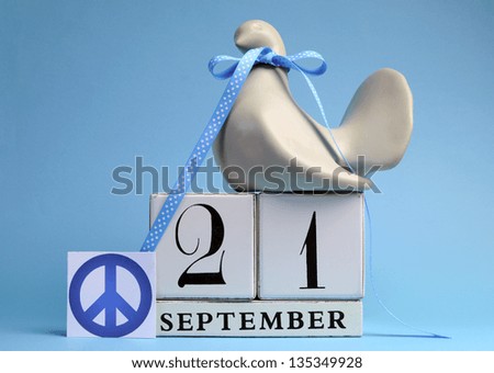 Dove and Peace Sign decorations for International Day of peace, World Peace Day, with white block calendar date on pale blue background.