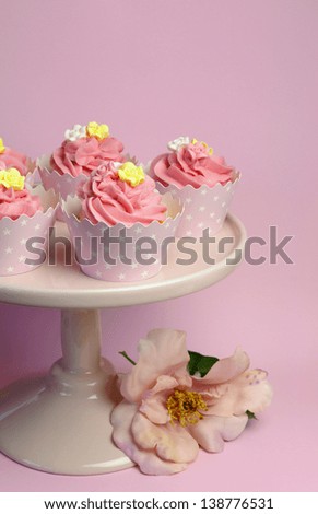 Beautiful pink decorated cupcakes on pink cake stand for birthday, wedding or female special event occasion. Vertical with pink rose flower.