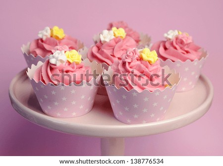 Beautiful pink decorated cupcakes on pink cake stand for birthday, wedding or female special event occasion, with pink, yellow and white fondant roses and pink star cups.