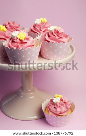 Beautiful pink cupcakes in star holders on pink cake stand for birthday, bridal, wedding, bachelorette or female special occasion event.