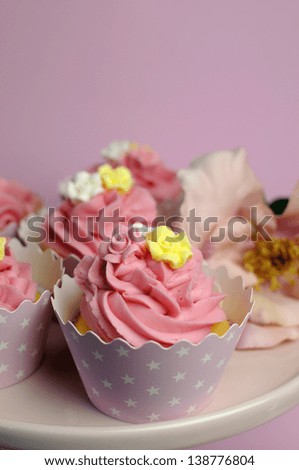Beautiful pink decorated cupcakes on pink cake stand for birthday, wedding or female special event occasion. Vertical close up with bokeh.