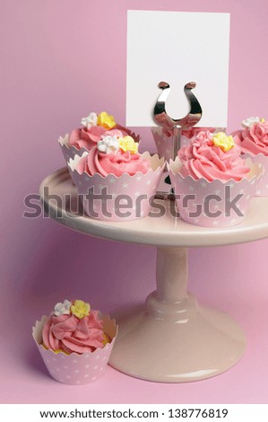 Beautiful pink decorated cupcakes on pink cake stand for birthday, wedding or female special event occasion, with blank card for your text here.