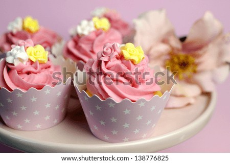 Beautiful pink decorated cupcakes on pink cake stand for birthday, wedding or female special event occasion. Close up with bokeh.