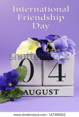 Save the Date white block calendar for August 4, International Friendship Day, decorated with blue and white pansy violas on blue purple background.