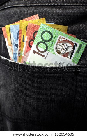 Australian money including 100, 50, 5, 10 and 20 dollar notes, in back pocket of a man\'s black charcoal jeans pocket. Vertical.