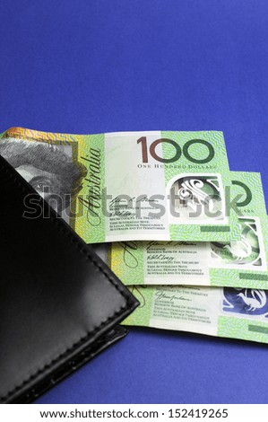 Three hundred Australian dollar green and yellow notes folding out from black wallet. Vertical.
