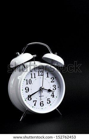 Beautiful white old fashion alarm clock against black background. Vertical.