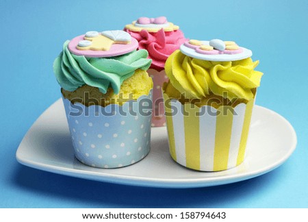 Beautiful pink, aqua blue and yellow cupcakes on white heart shape plate, for baby shower or children\'s party holiday and event.