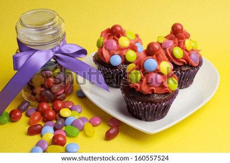 Colorful red blue yellow and red candy covered cupcakes with candy jar for Christmas, Halloween, or children birthday party