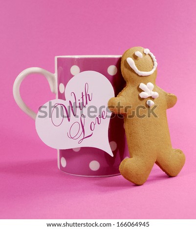 Merry Christmas ginger bread man with pink polka dot cup of coffee or tea mug and heart gift tag With Love message greeting against a pretty pink background.