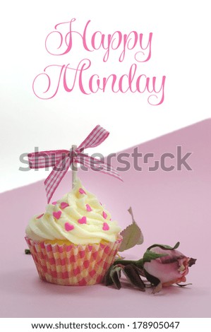 Pretty pink cupcake with pale pink silk rose bud on pink background with Happy Monday sample text or copy space for your text here.