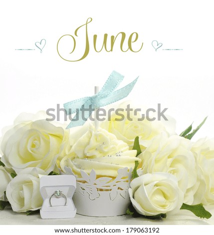 Beautiful white June Bride theme cupcake with seasonal flowers and decorations for the month of June with sample text or copy space for your text here.