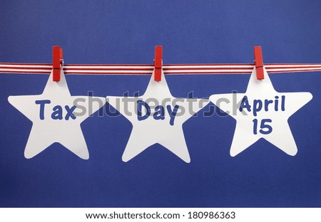 Tax Day April 15, for USA tax day reminder, greeting or message across white stars hanging from pegs on a line against a blue background.