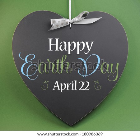 Happy Earth Day April 22, message sign greeting on a heart shaped blackboard against a green background.