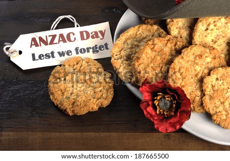 Australian army slouch hat and traditional Anzac biscuits on dark recycled wood with remembrance red poppy with Anzac Day, Lest We Forget tag.