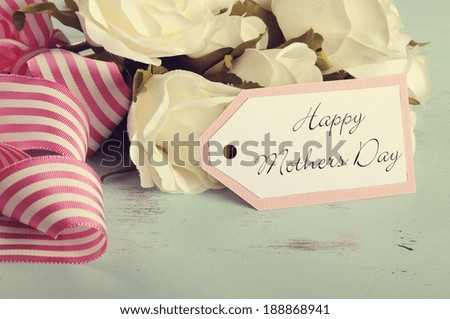 Retro style Happy Mothers Day gift of white roses bouquet with pink stripe ribbon and gift tag with greeting on aqua blue vintage shabby chic table.