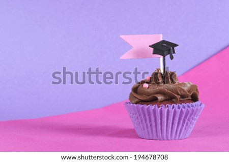 Graduation day pink and purple party cupcake on pink and purple background with copy space for your text here.
