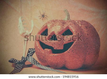 Retro vintage Happy Halloween party celebration jack o\'lantern pumpkin and skeleton glass, cobwebs and spider on grunge style filter orange background.