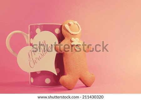 Merry Christmas ginger bread man with pink polka dot cup of coffee or tea mug and heart gift tag against a pretty pink background, with copy space for your text here  with retro vintage filter..