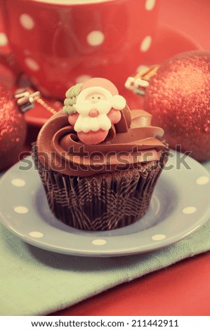 Christmas chocolate cupcakes with Santa faces against a red festive background with retro vintage filter..