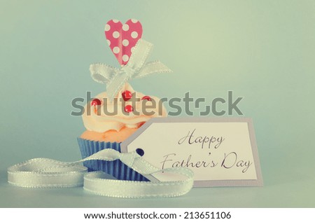 Happy Fathers Day cupcake with red and white decorations with heart topper on pale blue background with retro vintage style filter.