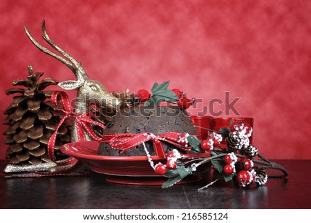 English style Christmas Plum Pudding dessert with traditional festive decorations, gold reindeer and berries against a red background.