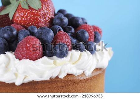 Fresh whipped cream and berries layer sponge cake closeup with copy space on pale blue background.