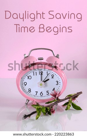 Daylight savings time begins clock concept for start at Spring against a pink background, with text message.