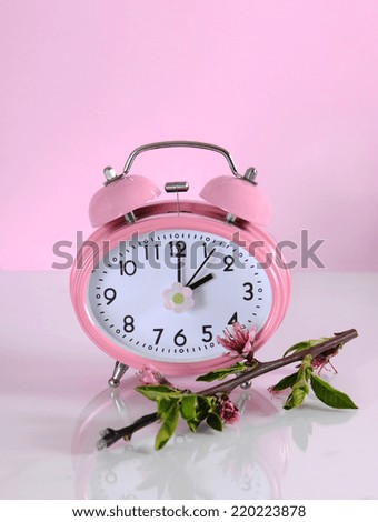 Daylight savings time begins clock concept for start at Spring against a pink background.