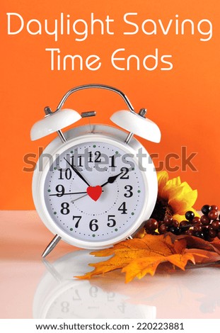 Daylight savings time ends in autumn fall with clock concept and text message on orange background.