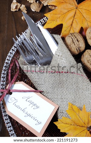 Happy Thanksgiving dining table place setting in traditional rustic country style with hessian wrapped cutlery on rustic wood background. Vertical closeup.