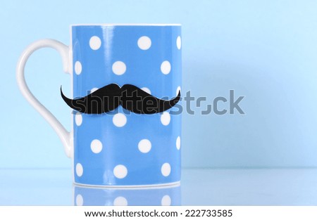 November fund raising for mens health awareness charity with mustache on blue polka dot coffee mug cup on blue background, with copy space.