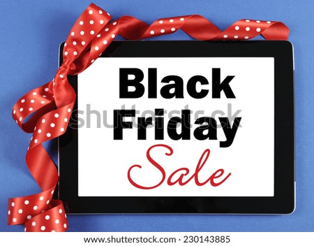 Black Friday Sale message on black computer tablet device with red ribbon on blue background.