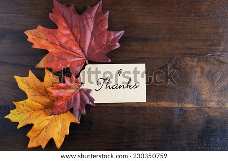 Thanksgiving table place setting with greeting tag and autumn fall leaves on rustic dark recycled wood background, with copy space.