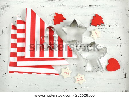 Festive Christmas Holiday background with red and white theme cookie cutters and stripe napkins on vintage shabby chic white wood background.