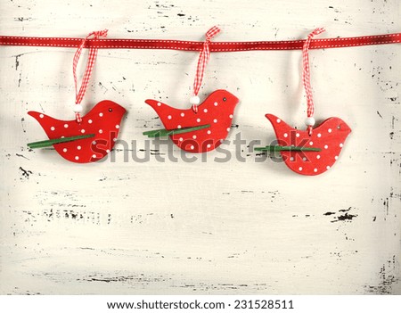 Festive Christmas Holiday background with red and white theme polka dot wood bird ornaments on vintage rustic shabby chic white wood background.
