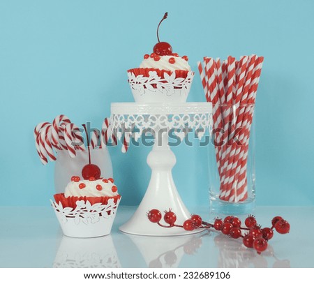 Christmas holiday dessert party food with red and white theme red velvet, cream and cherry cupcakes on pale blue and white background.