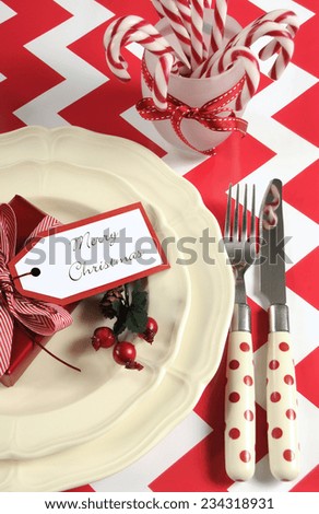 Bright colorful modern Christmas children family party table place settings in red and white theme on a chevron stripe table. Vertical.