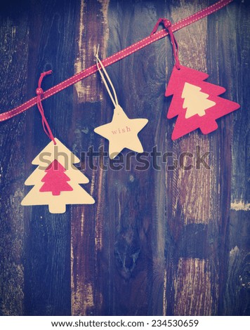 Christmas holiday background on dark recycled wood with festive hanging felt tree decorations, with retro vintage filter.
