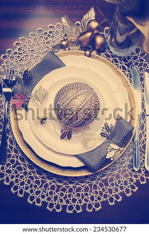 Latest trend of gold metallic theme Christmas  formal dinner table place setting with fine bone china, bauble and festive decorations, with retro vintage filter.