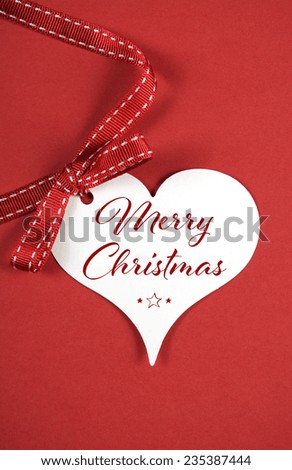 Merry Christmas greeting on white heart gift tag on red background, with sample text.