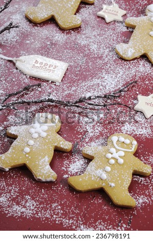 Merry Christmas festive baking concept with gingerbread cookies on red vintage style recycled wood background. Closeup angle.
