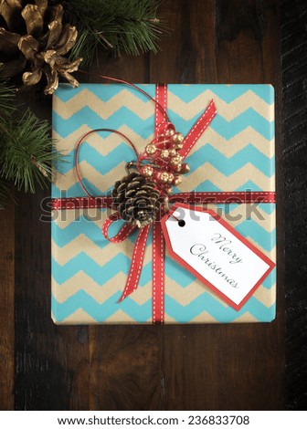 Festive Christmas gift box with chevron stripe wrapping on dark recycled wood table. Vertical.