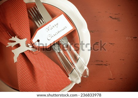 Retro vintage Christmas table place settings in red and white theme, on dark red recycled vintage distressed wood.