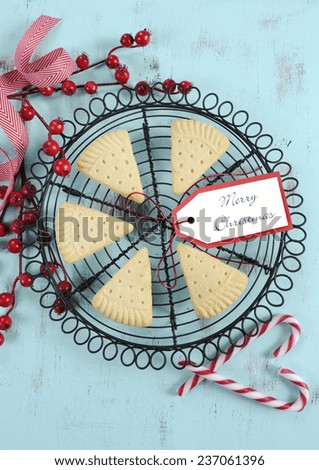 Traditional Christmas shortbread triangle shape cookies on vintage baking rack with festive decorations on recycled blue wood table. Vertical.