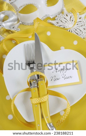 Bright and modern yellow and white theme Happy New Year table with heart shape plate on polka dot place setting. Vertical closeup.