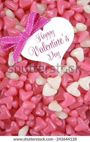 Valentines Day pink and white heart shape jelly candy confectionary on pink wood background with heart greeting card and sample text - vertical.