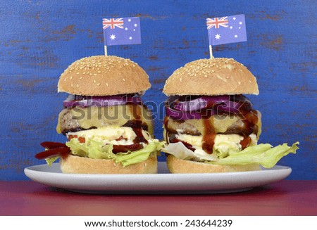 The Great Aussie BBQ Burger - with barbeque beef burgers and salad piled high with Australian flag against a red and blue distressed wood background.
