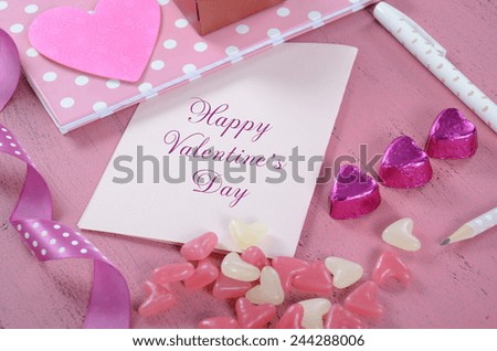 Writing love letters and cards for Happy Valentines Day with heart shape candy on pink shabby chic wood background - closeup.